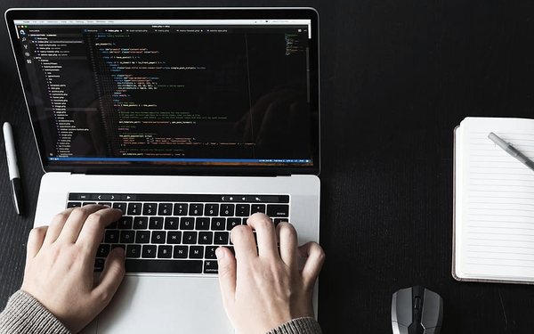 A developer writing code on a laptop